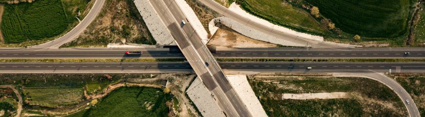 Vista aerea di uno svincolo autostradale con cavalcavia, tra campi verdi